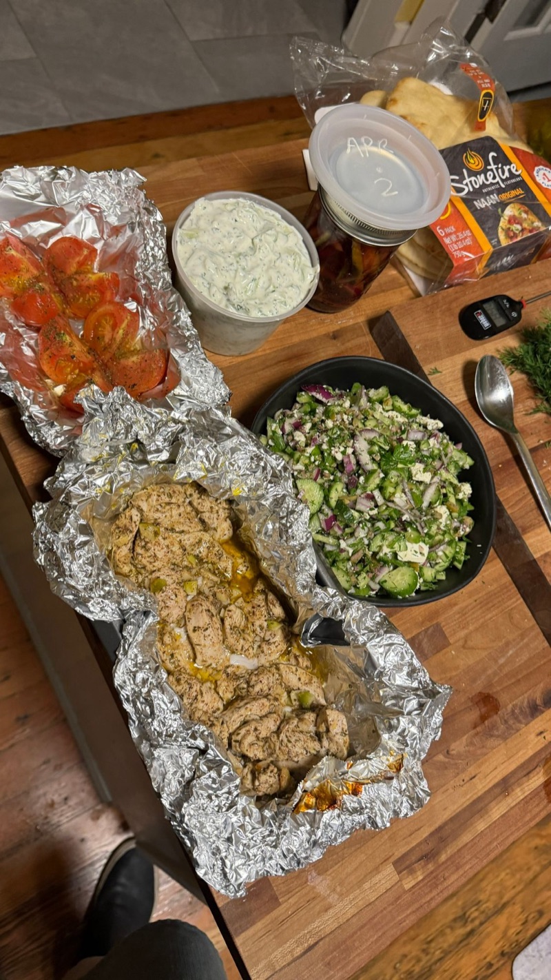 Homemade chicken döner spread with tzatziki, salad, roasted tomatoes, and naan