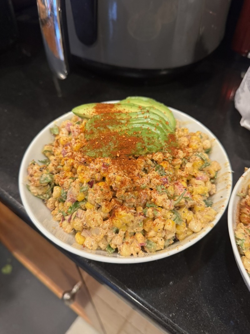 Mexican street corn salad topped with avocado and chili powder