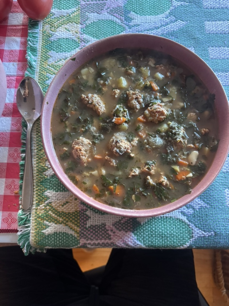 Bowl of Italian wedding soup with sausage meatballs and greens
